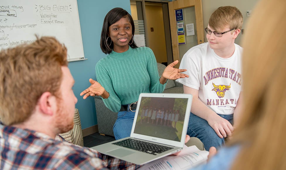 Four students in a meeting room in a discussion. 