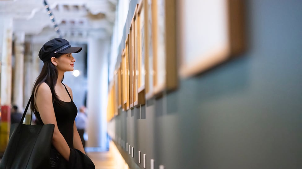 young woman in an art gallery looking at a picture on the wall