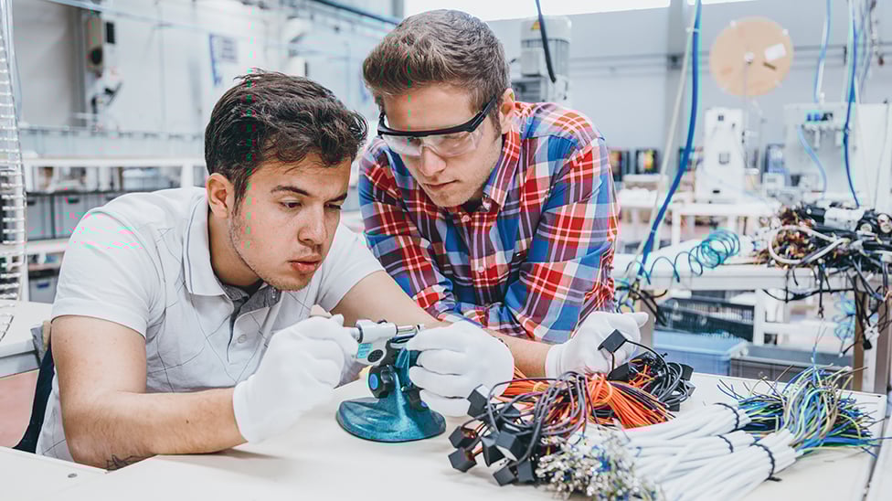 two students working on electrical wires in a lab