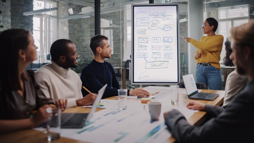 Group of men and women sitting at a computer talking about a project.