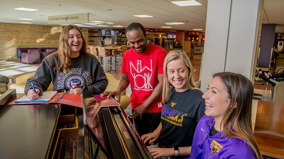 a group of people standing around a piano