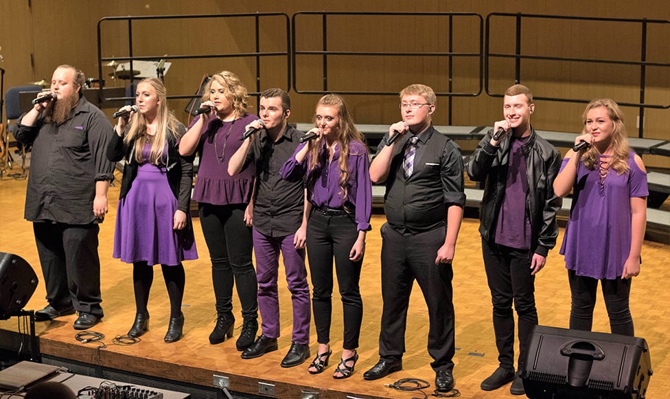 Students wearing Maverick purple performing and singing on stage