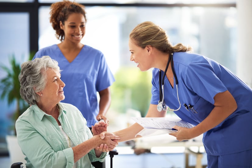 Nurse shaking the hand of an elderly women.