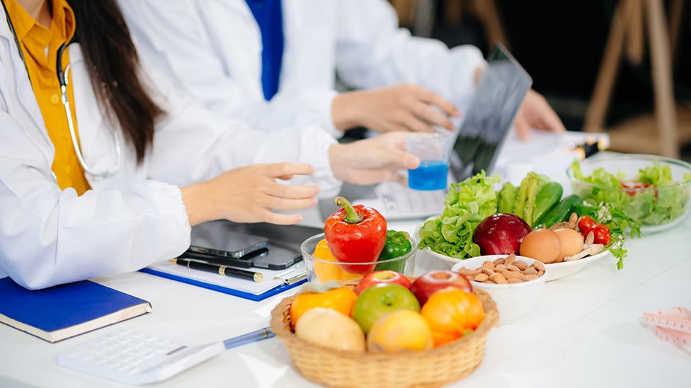 Dietitian writing diet plan, view from above on the table with different healthy products and drawings on the topic of healthy eating