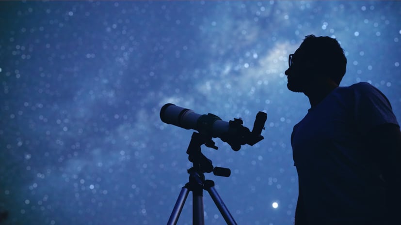 Night sky with a silhouetted telescope and student.
