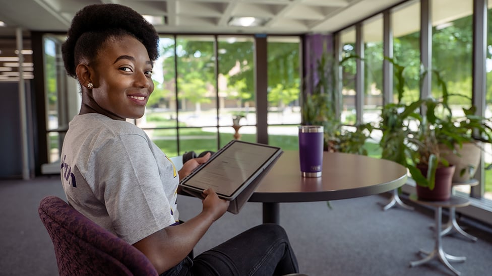 Women holding ipad looking at camera smiling. 