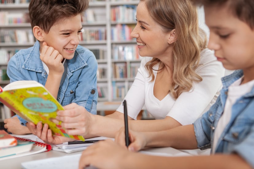 Women helping children read in a library.
