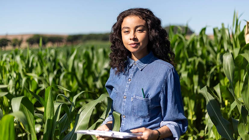 Diverse female agronomy student in a field with a tablet