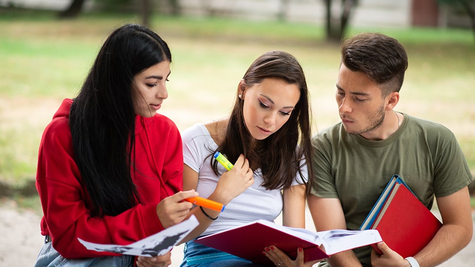 Three students sitting outside studying.