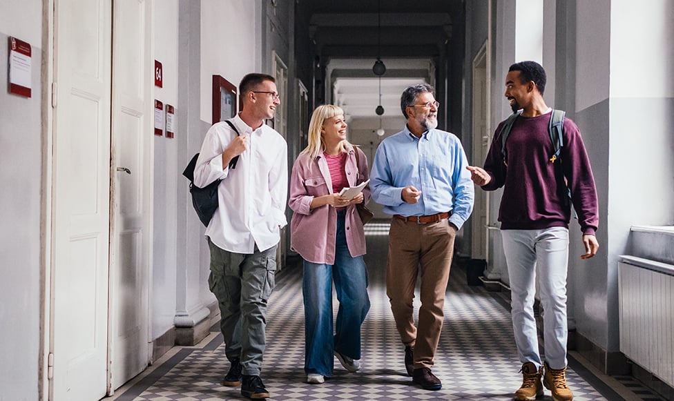 Four people walking down a hallway having a conversation.