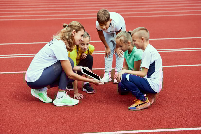 Coach talking to a group of students on a red track.