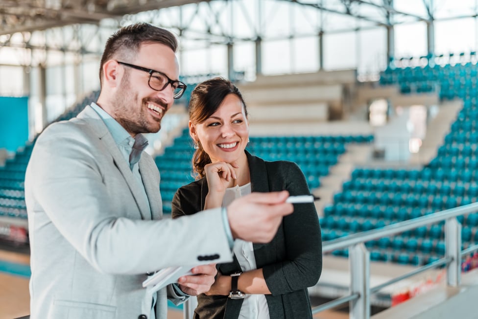 Business man talking with women in stadium.