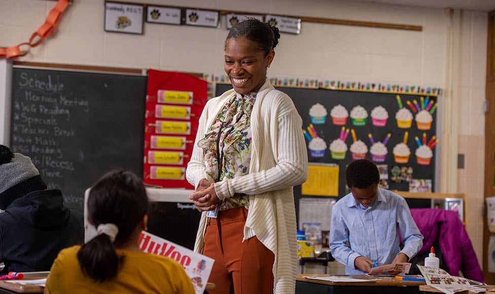 teacher standing in her classroom talking to an elementary aged student