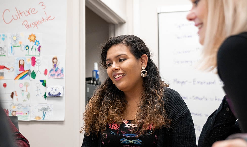 two teachers working with an elementary student at a white board