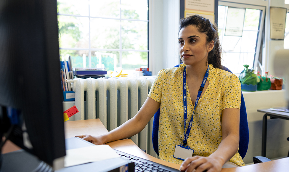 Women sitting at a desk looking in her computer.