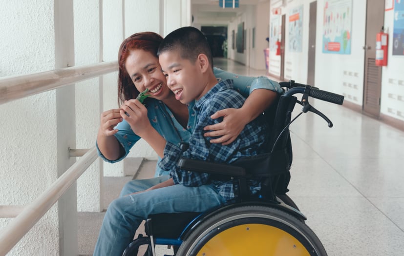 Aid talking with special needs child in wheelchair.