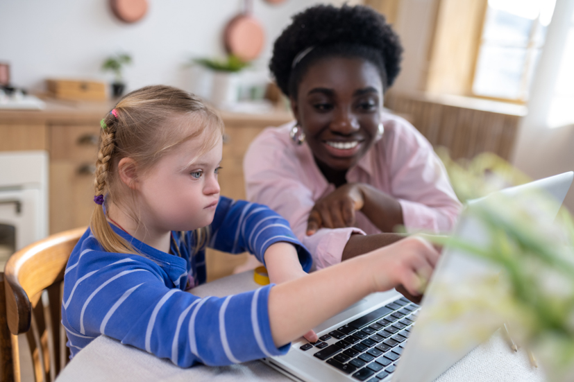 Teacher helping special needs child on computer.