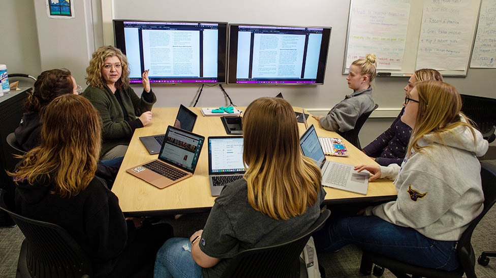 teacher sitting around a screen talking to special education students
