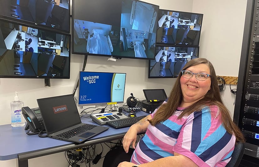Woman sitting a desk with computers in front of her.