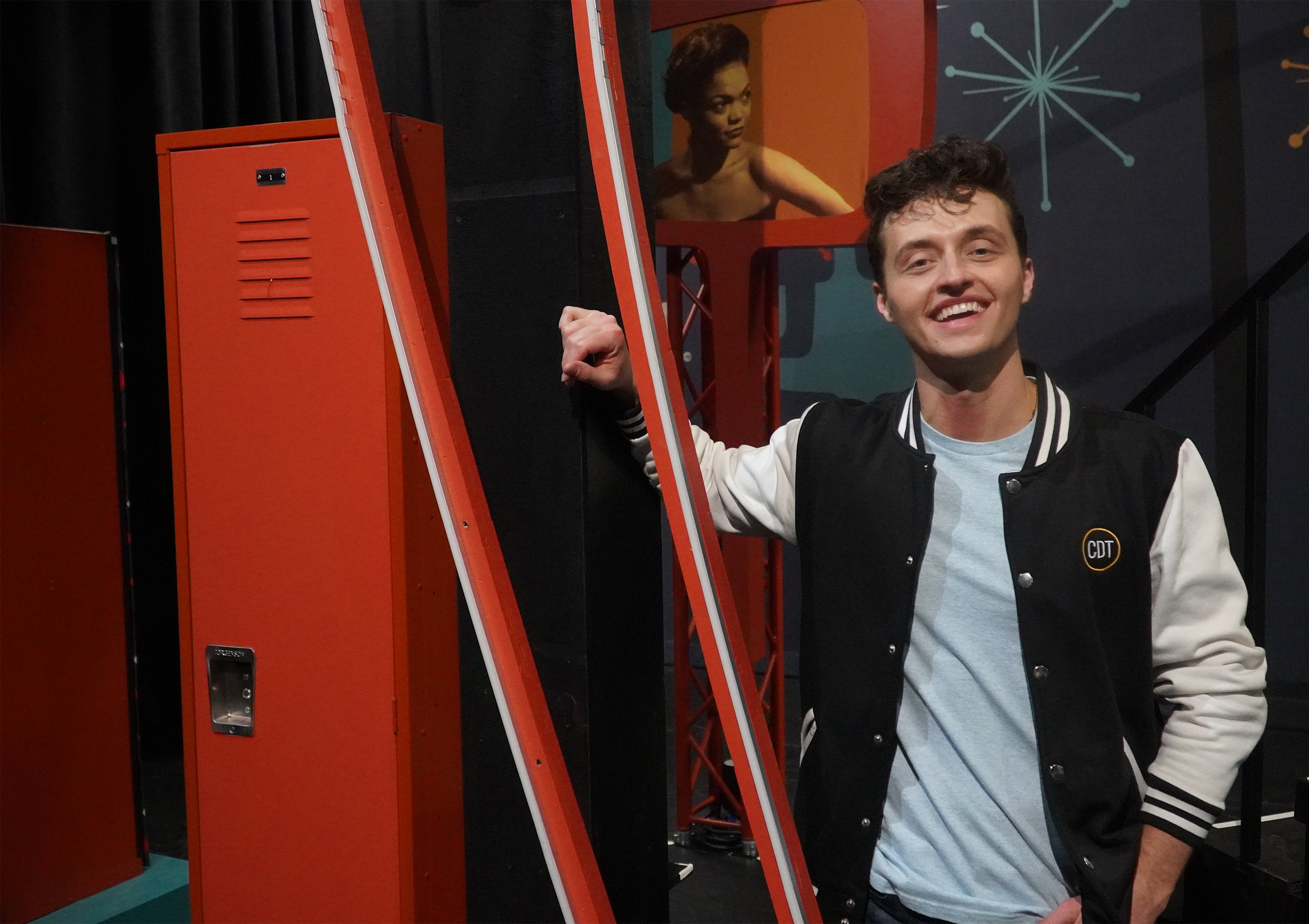 Man smiling and leaning against a red locker.