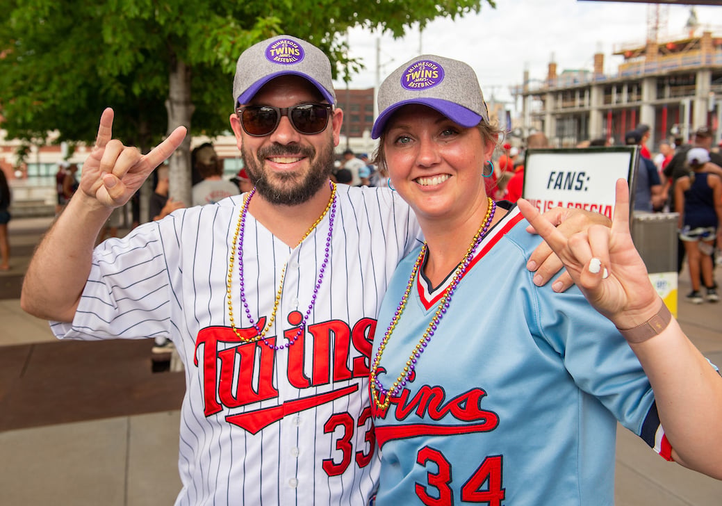 two MSU alumni at the twins stadium making the maverick hand sign