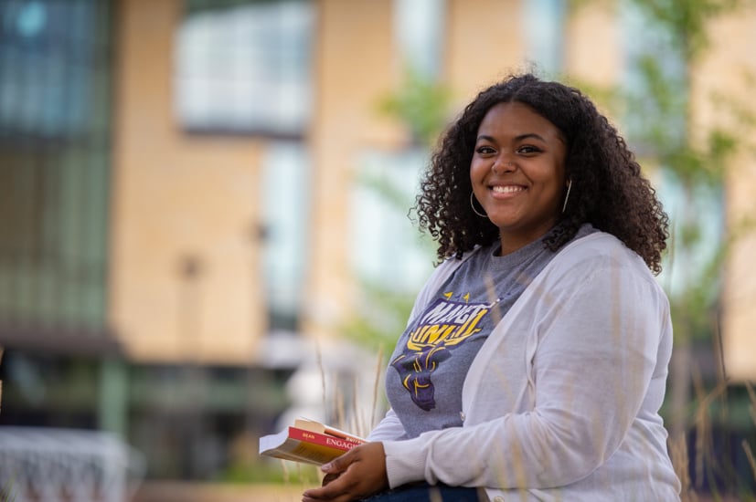 Women student sitting outside on campus in the summer. 