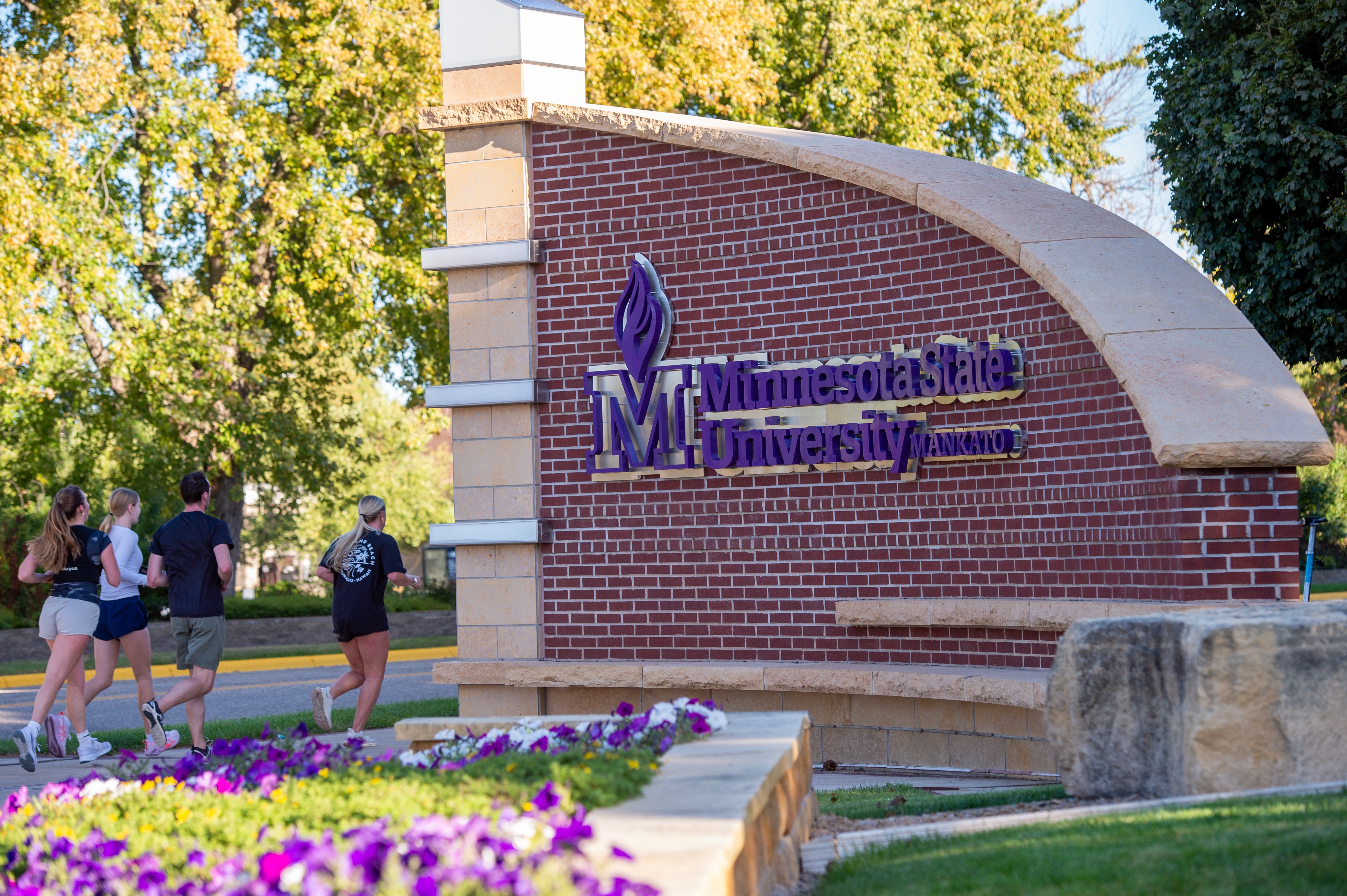 MSU entrance sign with students jogging nearby
