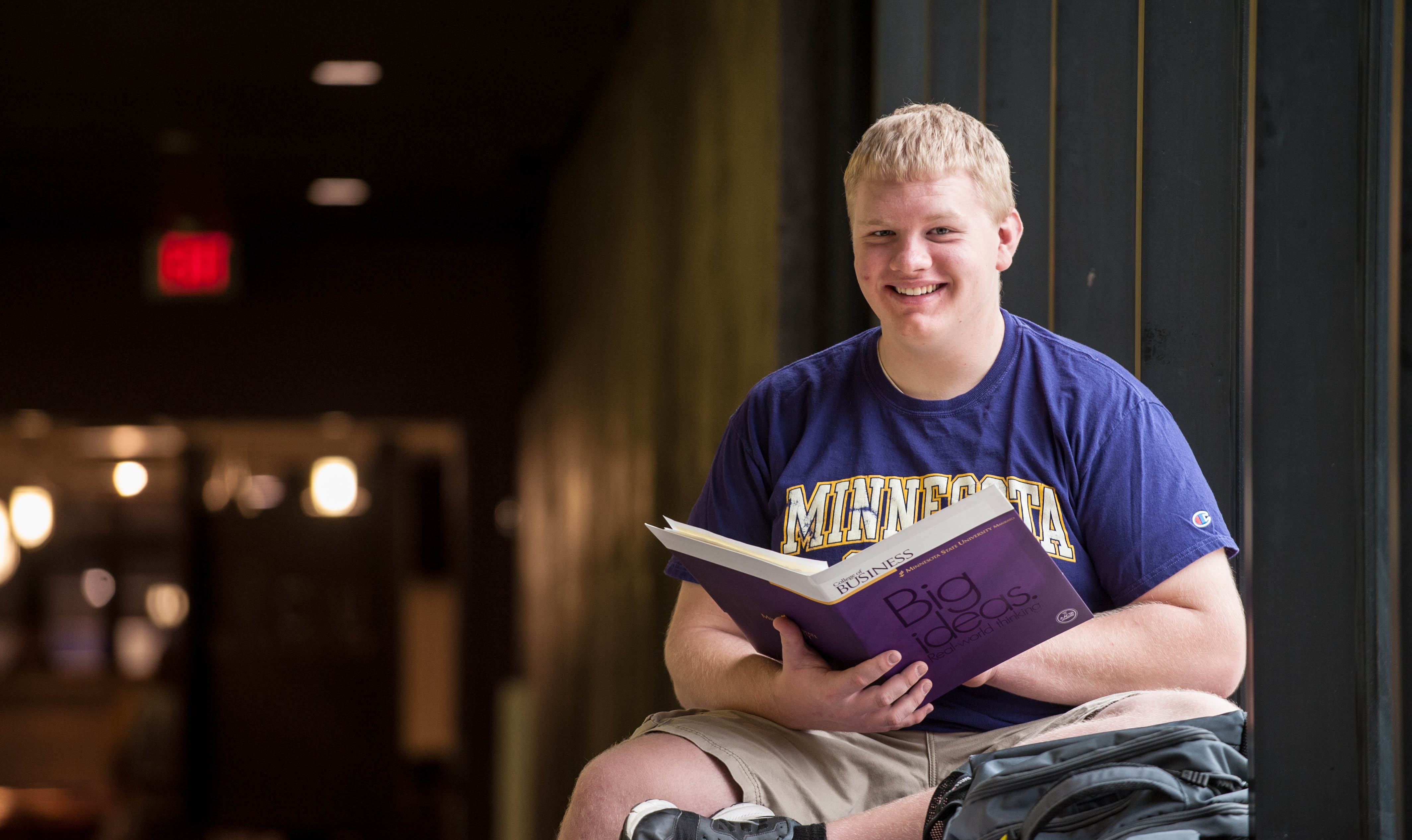 image of student sitting with a book and smiling
