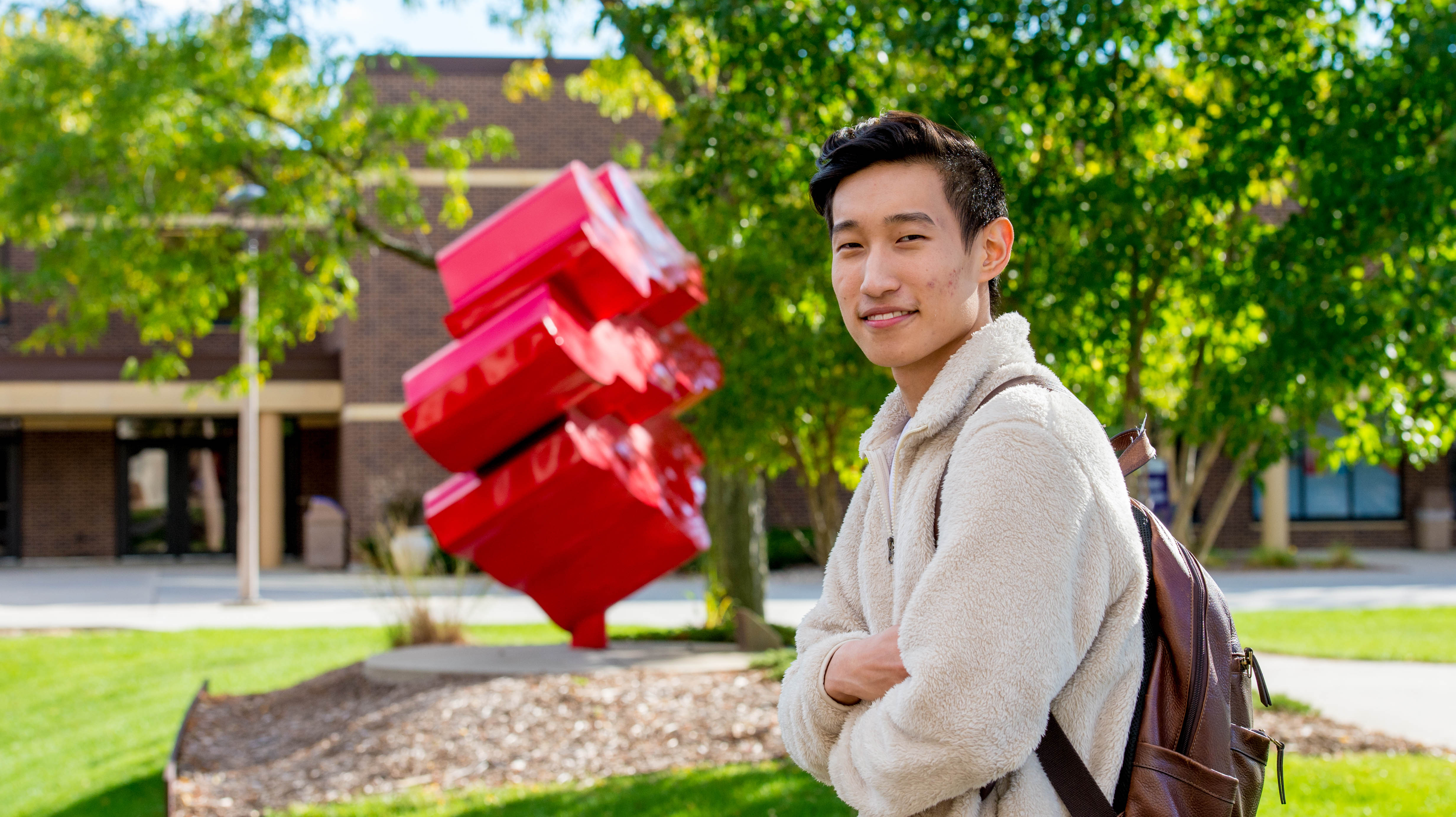 Graduate student with back pack on smiling