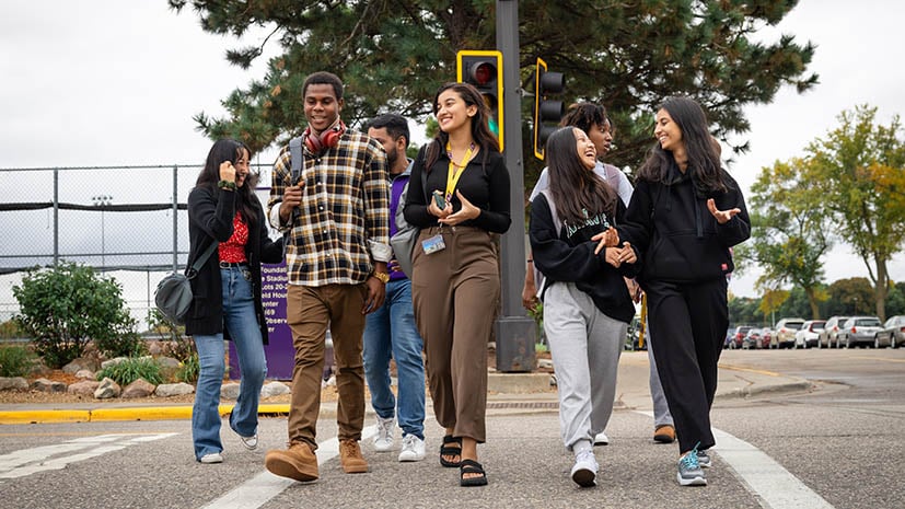 International Students walking across the street talking and laughing.