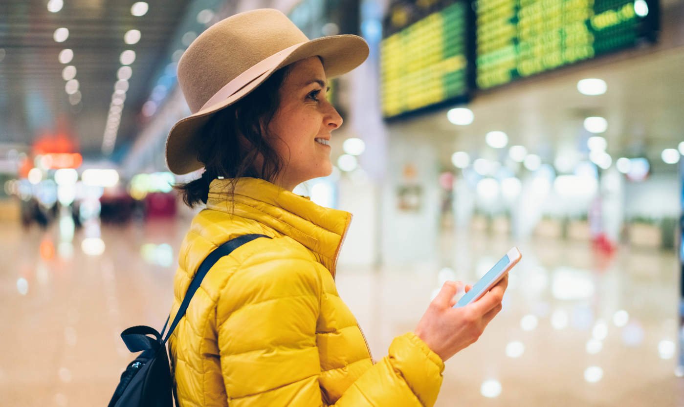 female student looking at her phone at the airport
