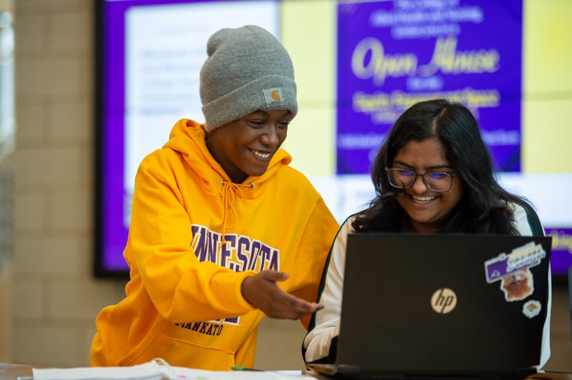 A female student helping another female student on the computer. 