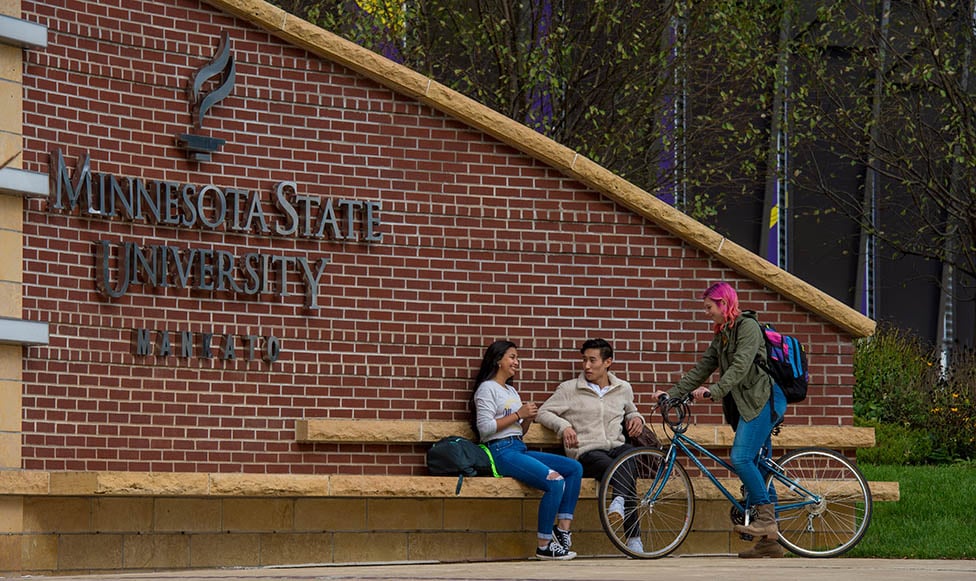 a group of people sitting on a bench in front of a sign