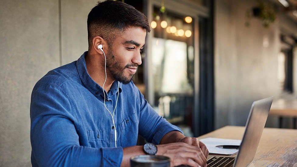 male student on laptop with headphones on