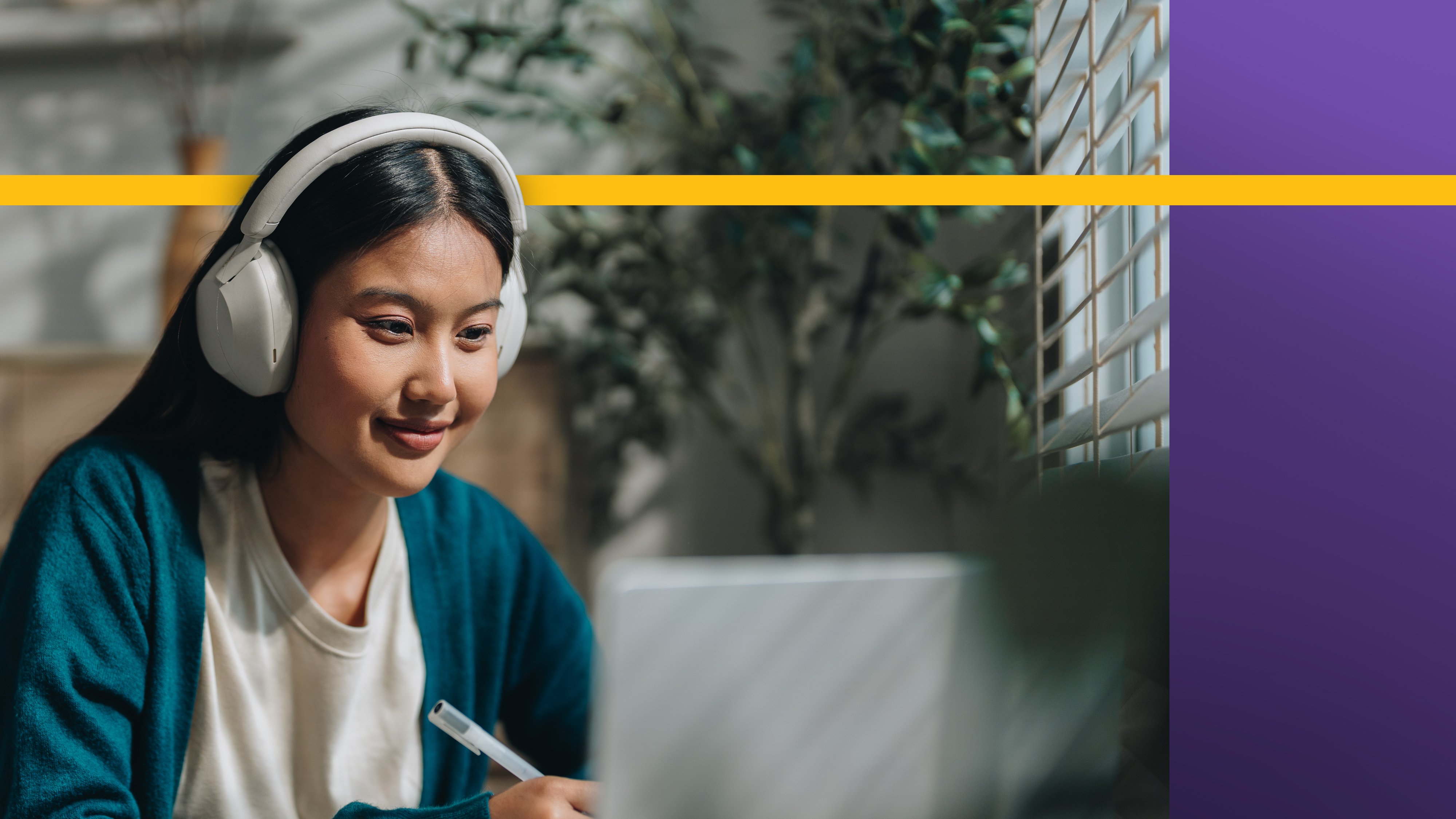 transfer student with headphones on doing school work while smiling
