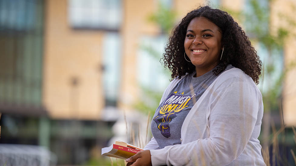 student sitting outside with campus in the background