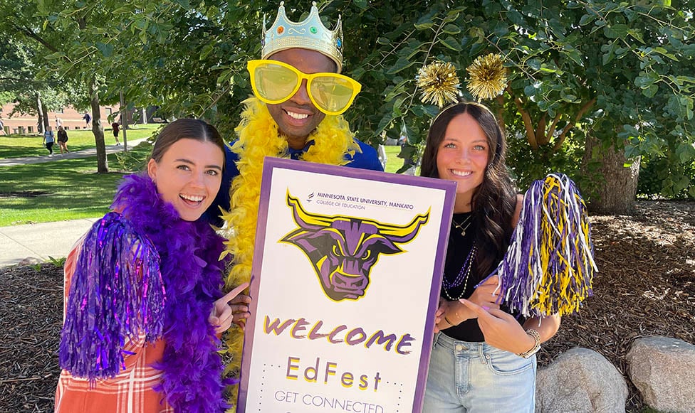 Dean of the College of Education posing with students holding an EdFest sign.