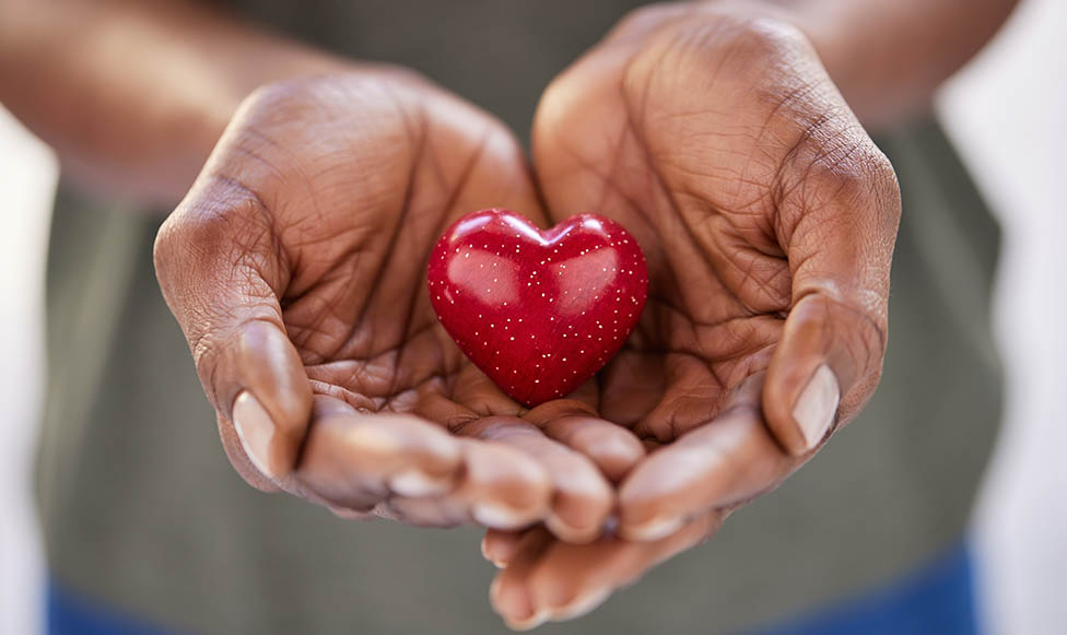 Two hands holding a red heart item.