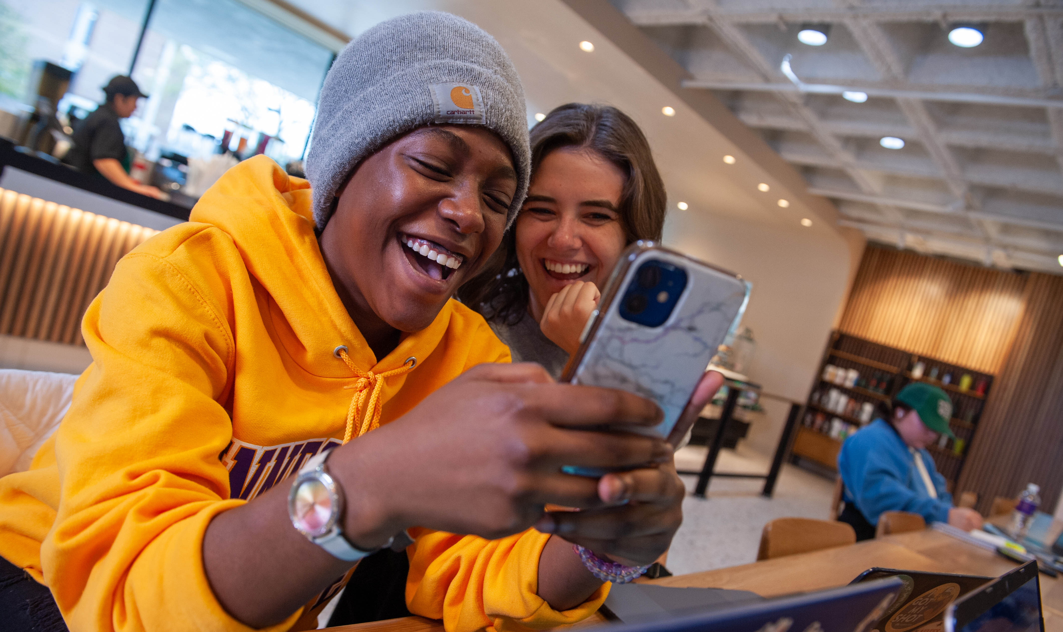 Image of two female students on their phone laughing at the centennial student union