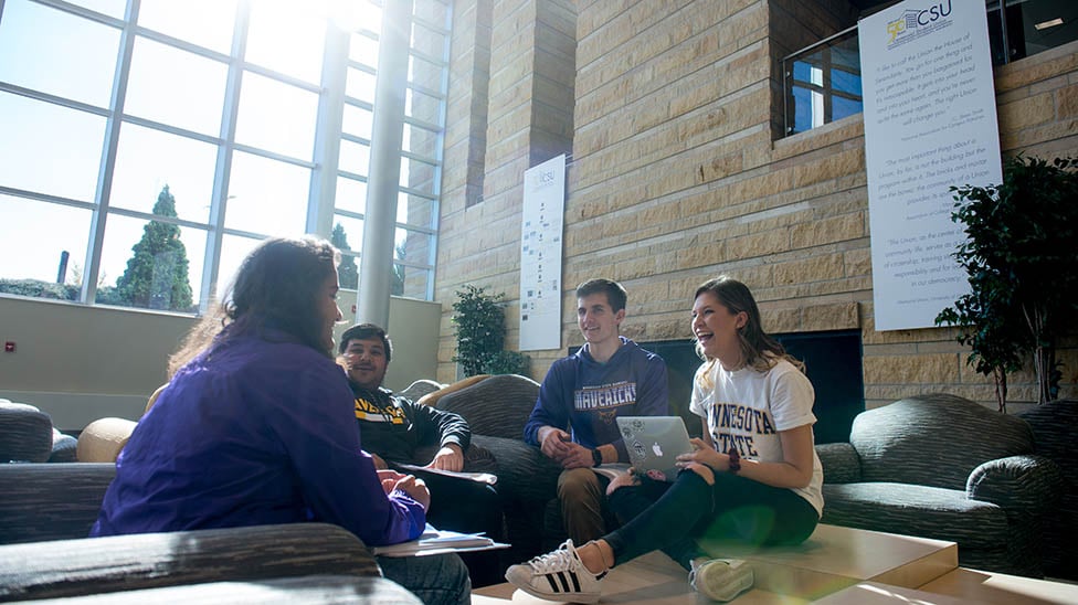 students chilling in the CSU, sitting in comfortable arm chairs, near the fireplace