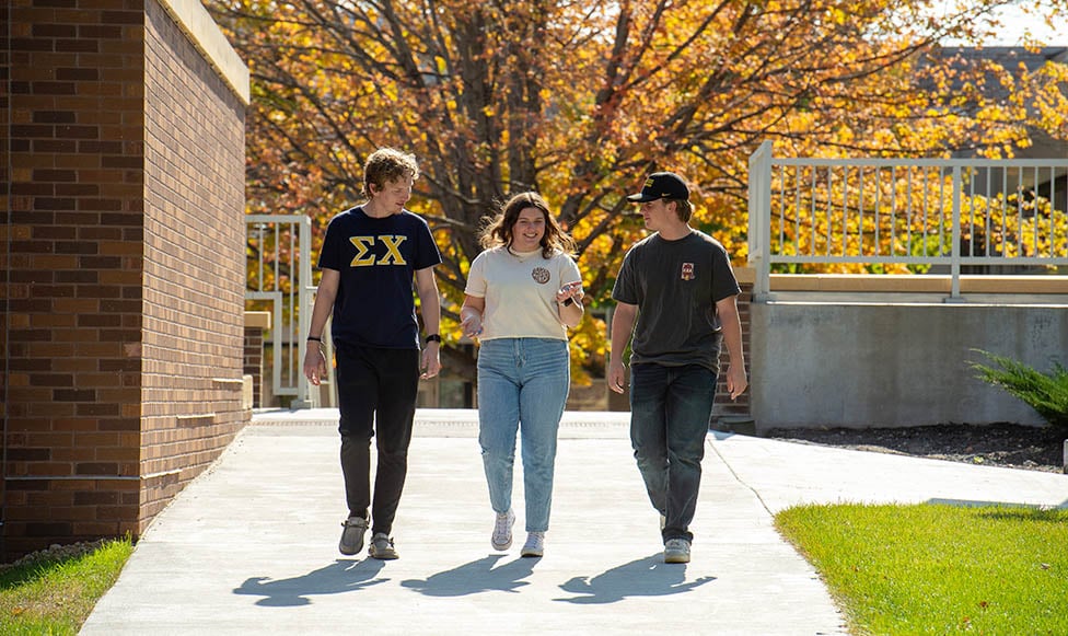3 students walking on campus with their fraternity and sorority shirts on