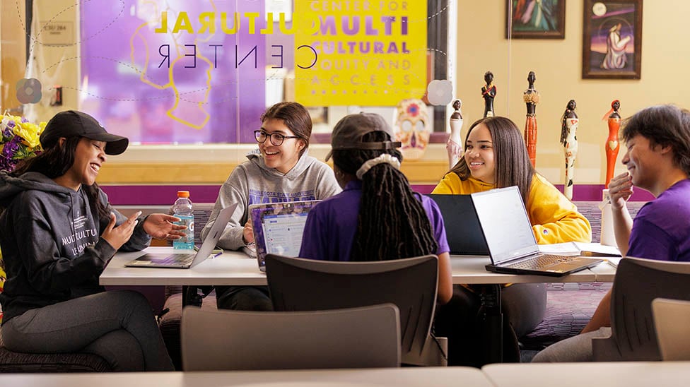 Five students sitting around a table in the MultiCultural Center