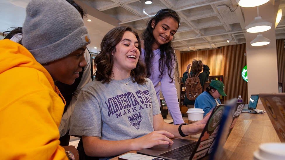 students gathered together sitting at a table laughing