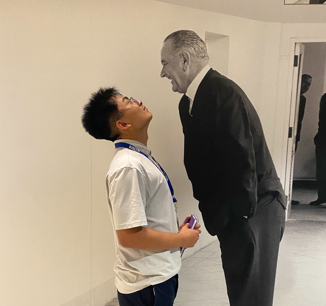 man standing face to face with life-size image of president LBJ looking up at him