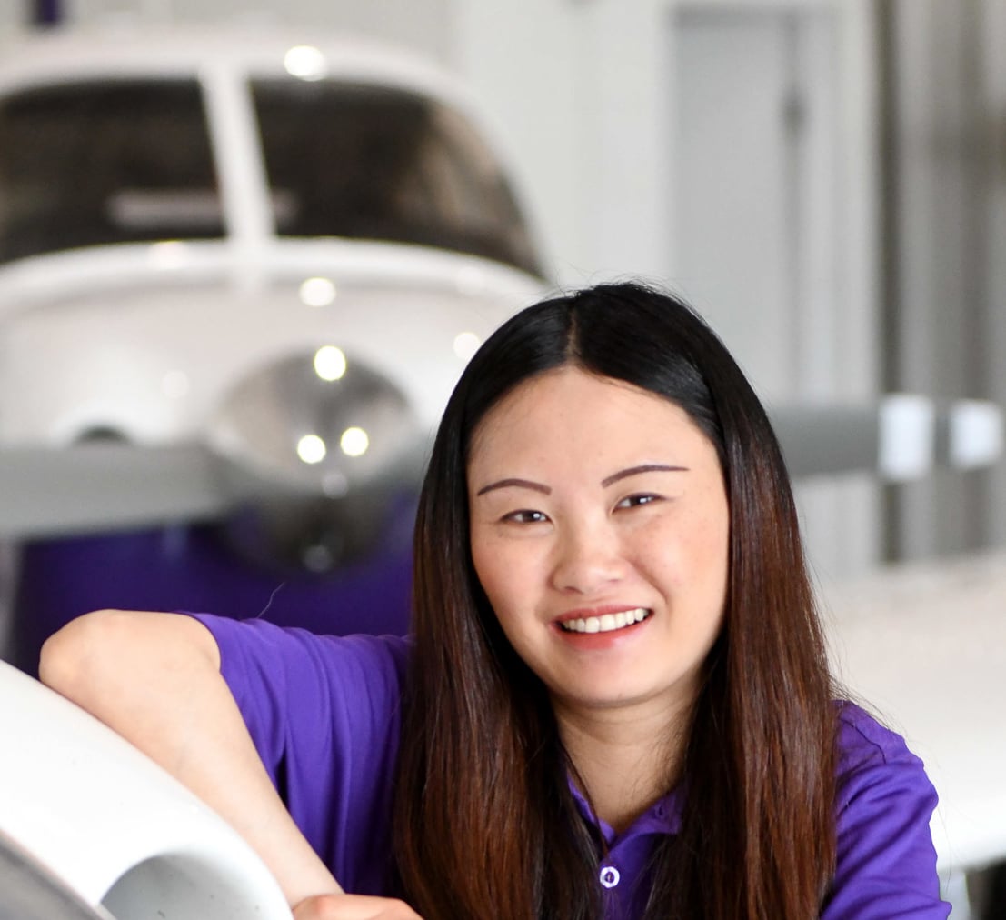 women with dark hair leaning again airplane with another airplane in the background