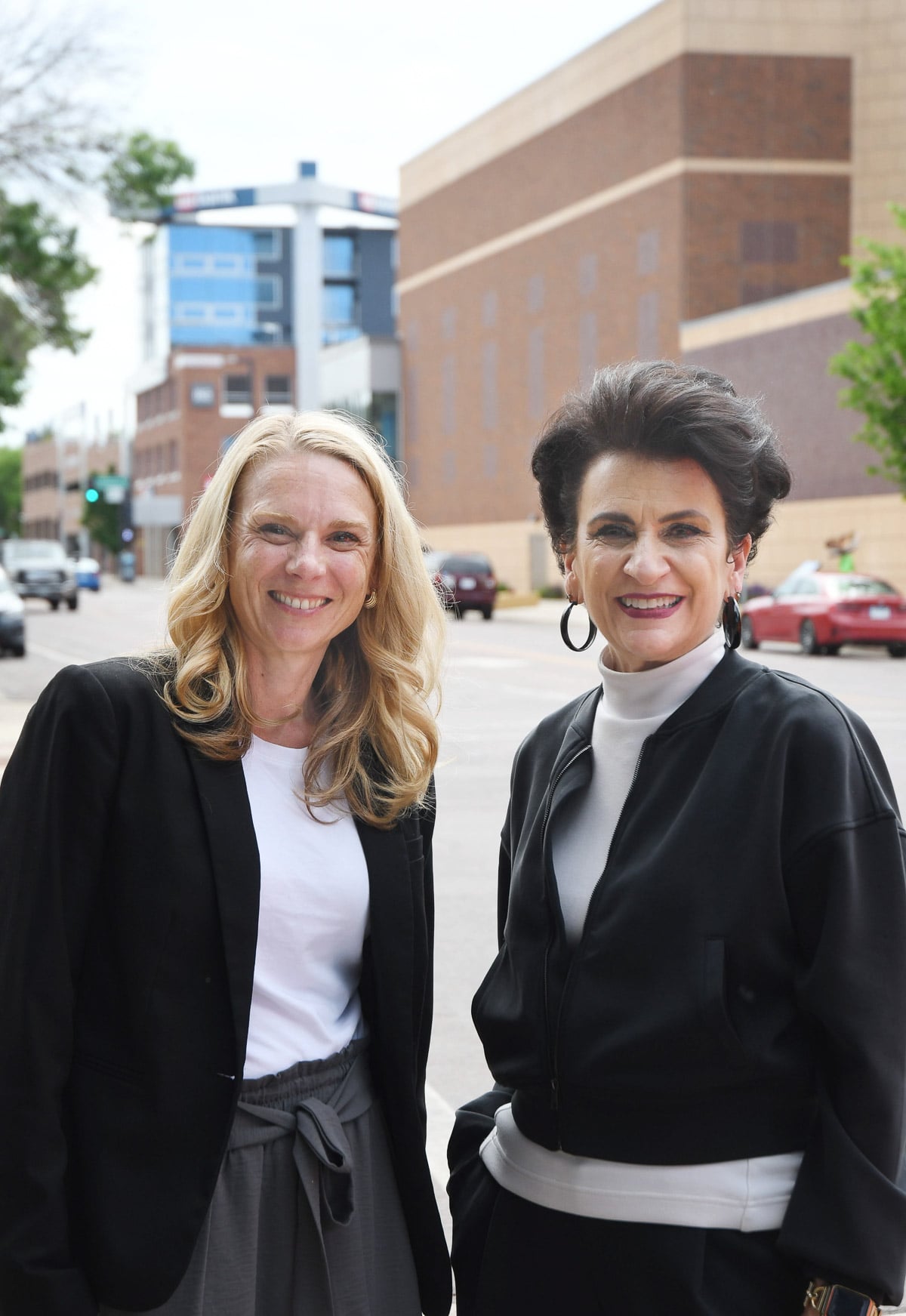 two women standing outside in front of office buildings
