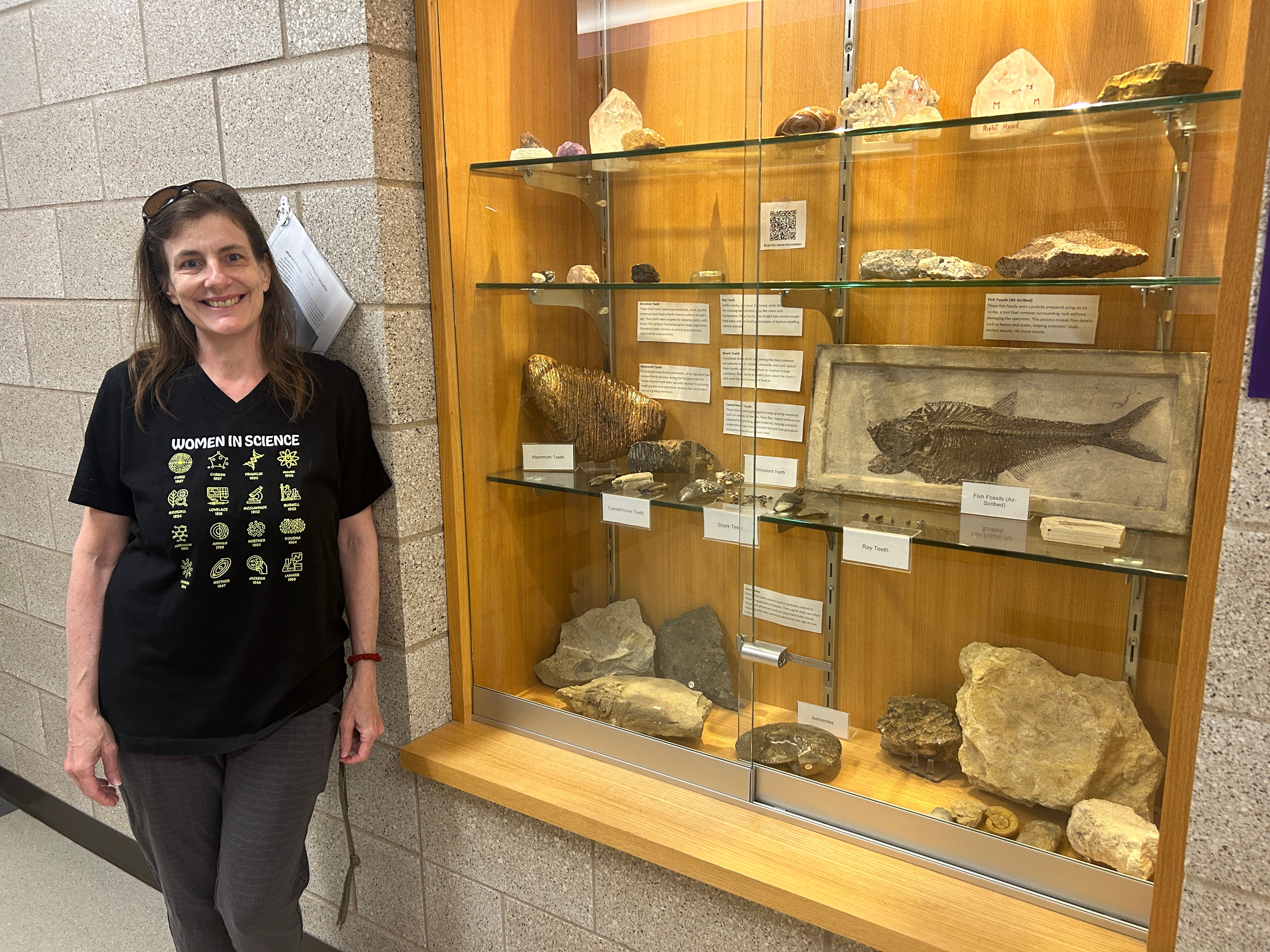 Professor Wisely standing near the glass showcase in an academic building showing the minerals, handwritten names and locations