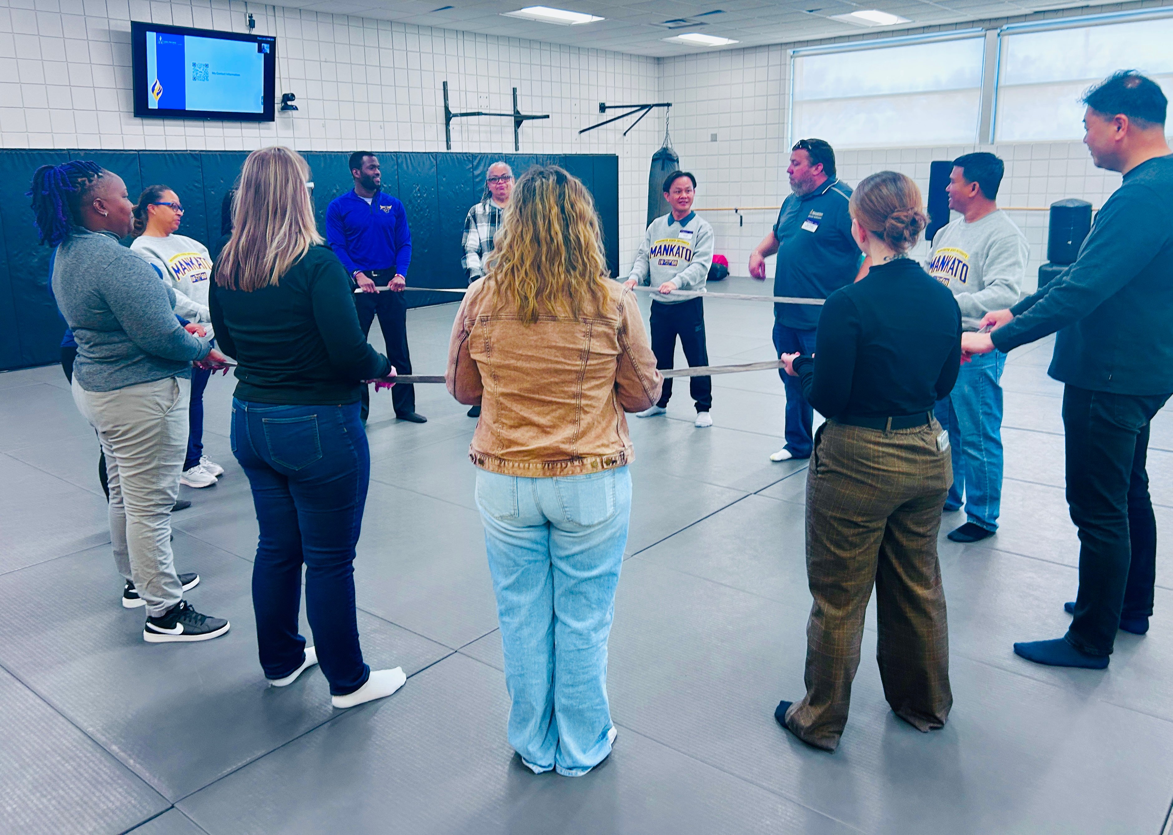 MSU staff leading a full group activity with all counselors in a circle and holding a rope as they listen to instructions