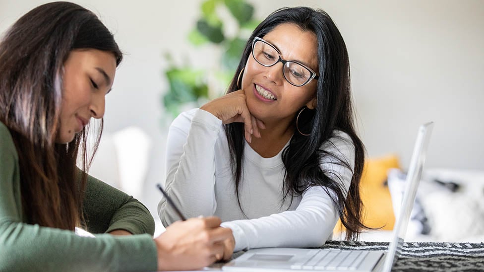 a person sitting at a table with a person and a laptop