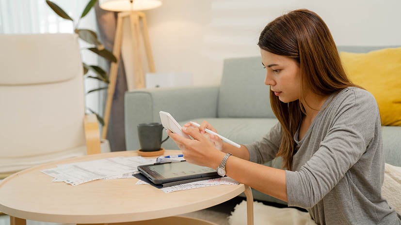 female student sitting in apartment with calculator and pen